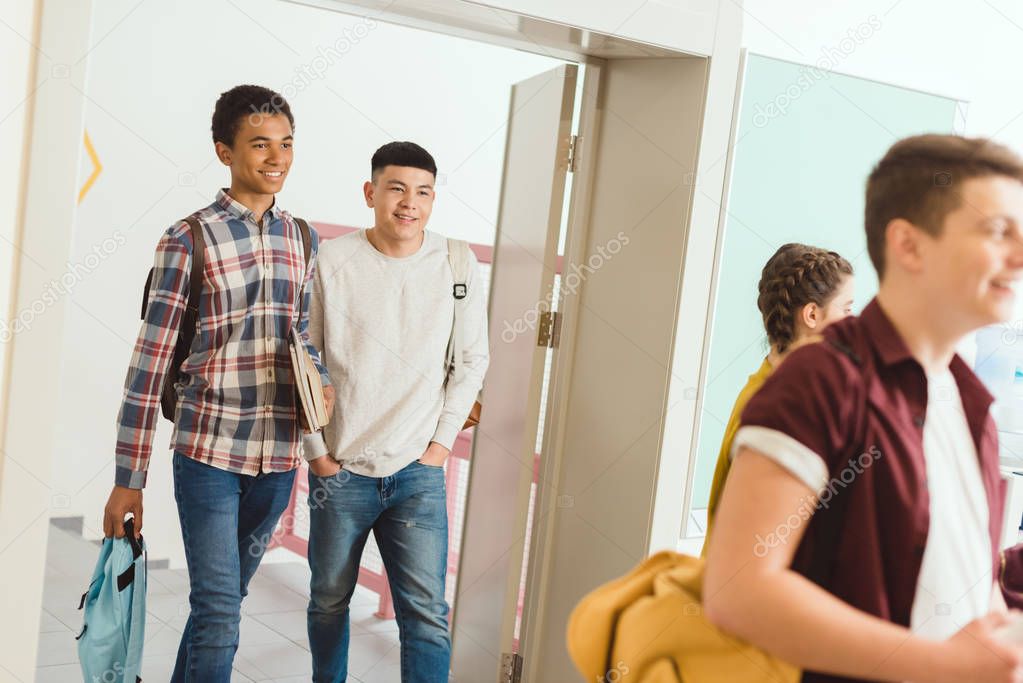 multiethnic high school students walking by school corridor