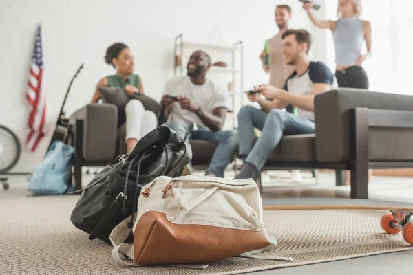 Närbild Skott Två Ryggsäckar Och Longboard Förgrunden Och Multietniskt Sällskap — Stockfoto