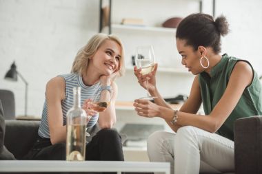 iki bardak beyaz şarap ile oturan çok kültürlü genç kadın gülümseyerek 