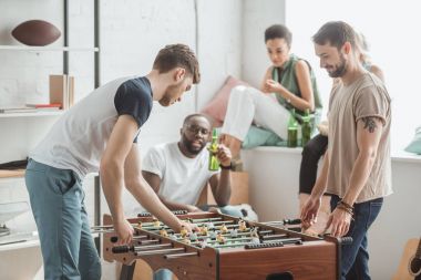 bira şişeleri ile izlerken onların arkadaşları süre masa futbolu oynayan iki genç adam yan görünüm 