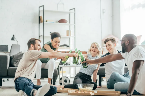 Amigos Multiétnicos Felizes Sentados Chão Clinking Com Garrafas Cerveja — Fotografia de Stock