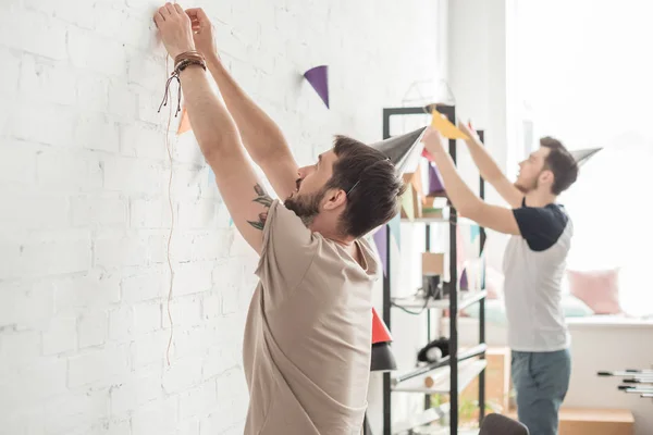 Zijaanzicht Van Twee Jonge Mannen Feestmutsen Tekenreeks Met Partij Slingers — Stockfoto