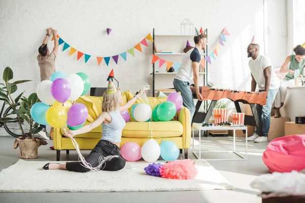 Young Woman Sitting Floor Colorful Balloons Her Friends Decorating Room — Stock Photo, Image