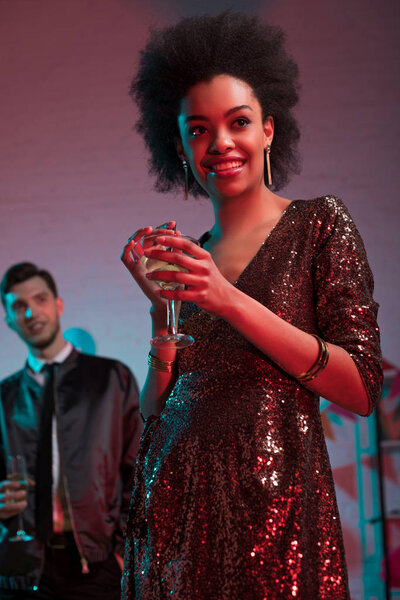 African american woman holding glass with cocktail by man at party