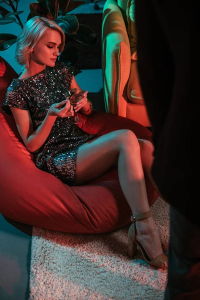 Λαμπερή Γυναίκα Κάθεται Στο Beanbag Και Κρατώντας Ποτήρι Κοκτέιλ — Δωρεάν Φωτογραφία