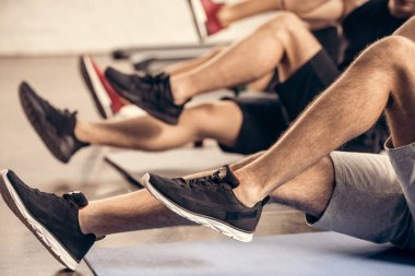 cropped image of sportsmen doing sit ups together in gym clipart