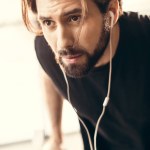 Close-up view of bearded young sportsman training and looking away in gym