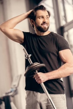 demir çubuk tutarak ve saç spor salonunda dokunmadan gülümseyen sporcu