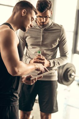 yakışıklı eğitmen tablet için sporcu spor salonunda egzersiz sayfa bulundu