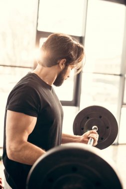 yakışıklı sporcu ile Halter salonunda eğitim yan görünüm