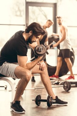 spor salonunda dumbbells ile eğitim yakışıklı kaslı adam yan görünüm