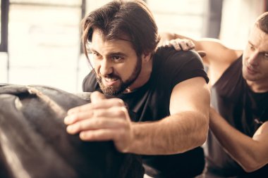 odaklı sportif genç adam lastik içinde jimnastik salonu kaldırma