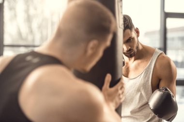 seçici odak eğitmen ve kum torbası içinde jimnastik salonu ile eğitim boxer