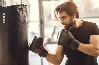 Boks eldiven kum torbası içinde jimnastik salonu ile egzersiz genç sporcu yan görünüm