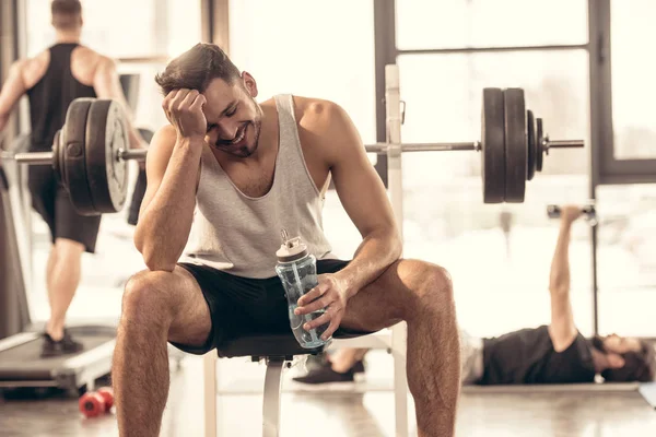 Lächelnder Sportler Sitzt Mit Wasserflasche Auf Bankdrücken Fitnessstudio — Stockfoto