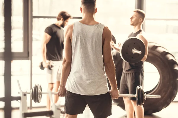 Baksidan Muskulös Ung Man Lyfta Skivstång Och Tittar Vänner Gymmet — Stockfoto