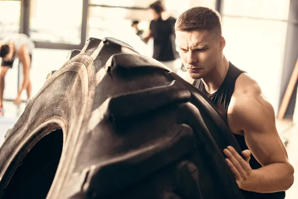 Beau Jeune Homme Musclé Faisant Exercice Avec Pneu Dans Salle — Photo gratuite