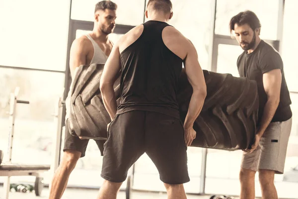 Jóvenes Deportistas Musculosos Levantando Neumáticos Juntos Gimnasio — Foto de Stock