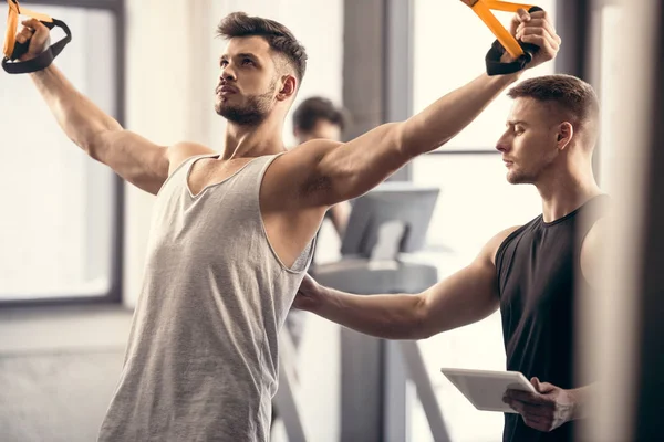 Jovem Treinador Com Tablet Digital Olhando Para Desportista Exercitando Com — Fotografia de Stock