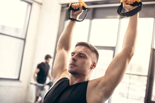 Guapo Joven Entrenamiento Con Correas Suspensión Mirando Hacia Otro Lado — Foto de stock gratuita