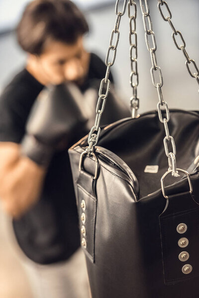 Крупный план боксерской груши и молодого боксера в тренажерном зале
