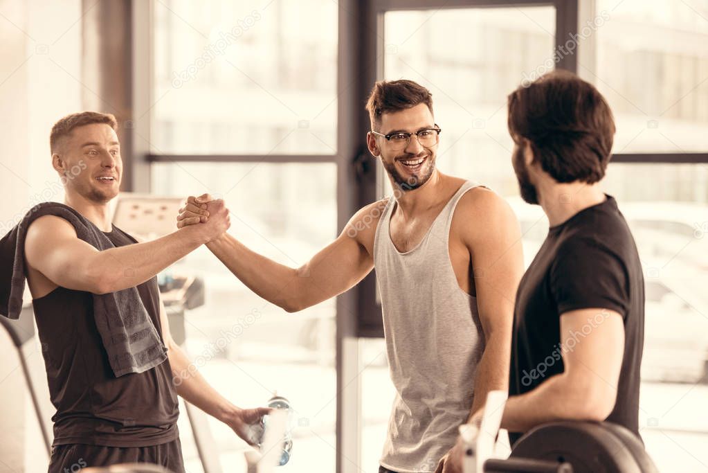 handsome smiling sportsmen greeting in gym