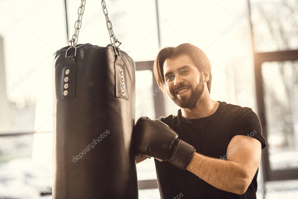 handsome young man boxing and smiling at camera in gym