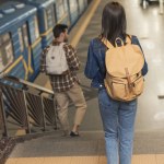 Вид ззаду стильних мандрівників з рюкзаками, що йдуть вниз на станції метро