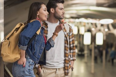 parmakla tarafından metro istasyonunda erkek sırt çantası ile kadın Gezgin gülümseyen 