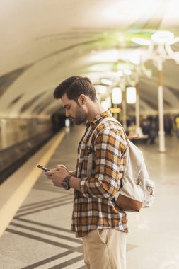 sırt çantası ve smartphone metro istasyonundaki adamla yan görünüm