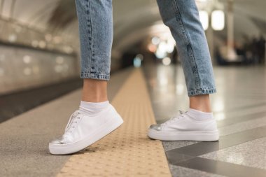 şık kot pantolon ve spor ayakkabı metro istasyonunda kadın bacak kırpılmış görüntü 