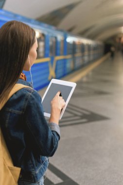 Dikiz kulaklık ve metro istasyonunda dijital tablet ile şık kadın 