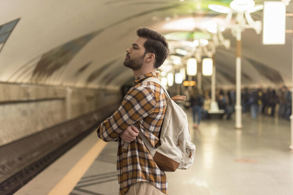 side view of stylish man with closed eyes waiting train at subway station