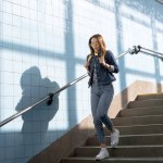 Junge stylische Touristin mit Sonnenbrille und Rucksack geht in U-Bahn die Treppe hinunter