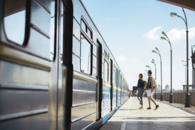 Tren açık metro istasyonunda girmeden sırt çantaları ile turist çiftin uzak görünümü 