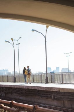 distant view of stylish couple of tourists going at outdoor subway station  clipart