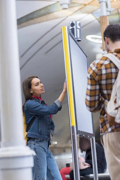 バックパックと彼のガール フレンドは 地下鉄の駅の案内板を見て男性の観光客の背面図  — 無料ストックフォト