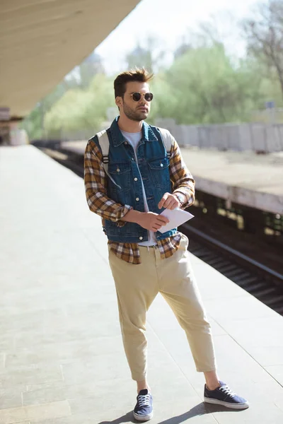 マップ手に屋外の地下鉄駅で電車を待っているとサングラスで若い男性の観光客  — 無料ストックフォト