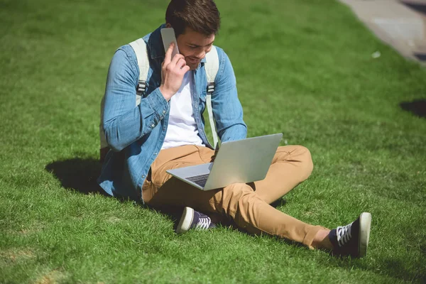 Стильный Мужчина Разговаривает Смартфоне Помощью Ноутбука Траве — стоковое фото