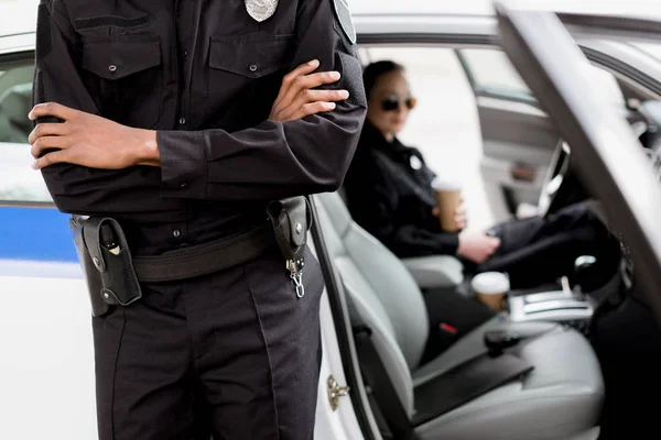 警察の車の前に立っている組んだ腕で警官のクロップ撮影 ロイヤリティフリーのストック画像
