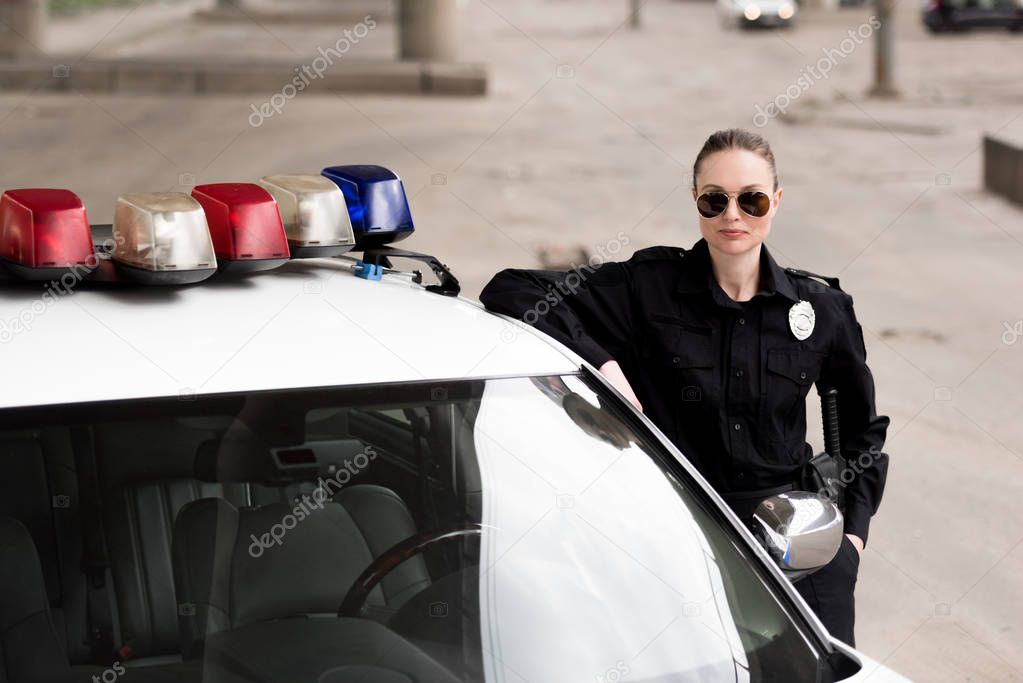 female police officer leaning on patrol car