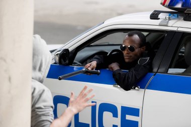 Afro-Amerikan polis polis sopası ile kukuletalı adam pencereden dışarı bakarken durdurma