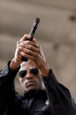 Afro-Amerikan Polis tabanca tarafından hedefleyen güneş gözlüğü düşük açılı görünüş 
