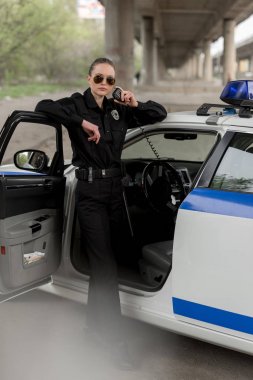 Polis arabanın yakınında duran ve taşınabilir radyo konuşurken güneş gözlüğü