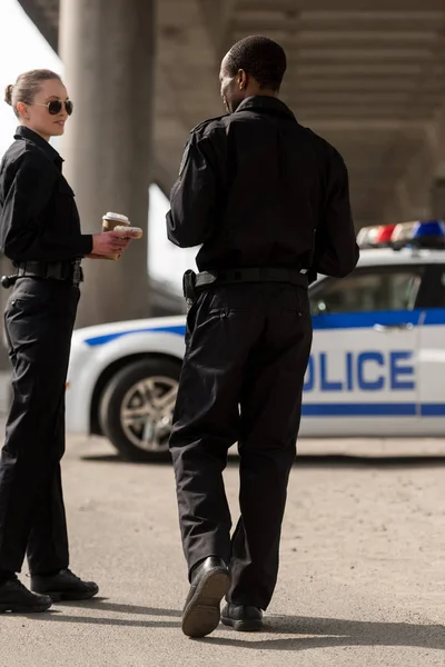 Улыбающиеся Полицейские Делают Перерыв Кофе Болтают Перед Машиной — Бесплатное стоковое фото