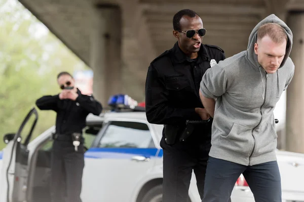 Θυμωμένος Αφρικανικός Αμερικανός Αστυνομικός Συλλαμβάνοντας Νεαρό Άνδρα Ενώ Σύντροφο Που — Φωτογραφία Αρχείου