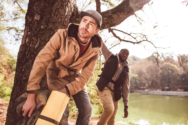 Uomini backpackers in piedi vicino al fiume — Foto stock