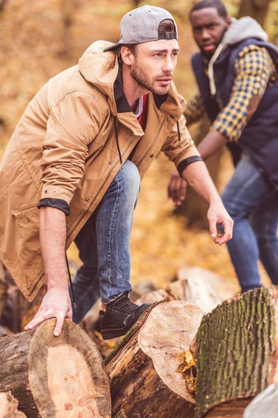 Young men near dry stumps in forest — Stock Photo