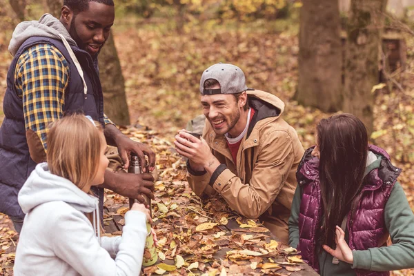 Amigos derramando bebida quente na floresta — Fotografia de Stock