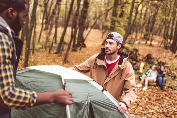 Homens lançando barraca na floresta de outono — Fotografia de Stock